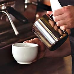 Aufgeschäumte Milch in Cappuccino Tasse füllen Aufgeschäumte Milch in Tasse füllen